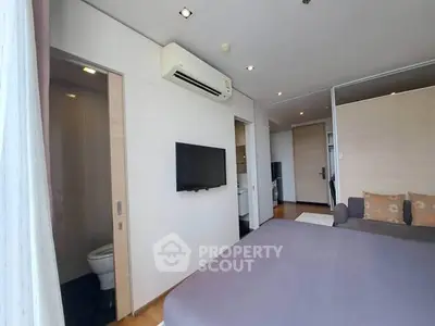 Modern bedroom with ensuite bathroom and wall-mounted TV in a stylish apartment.