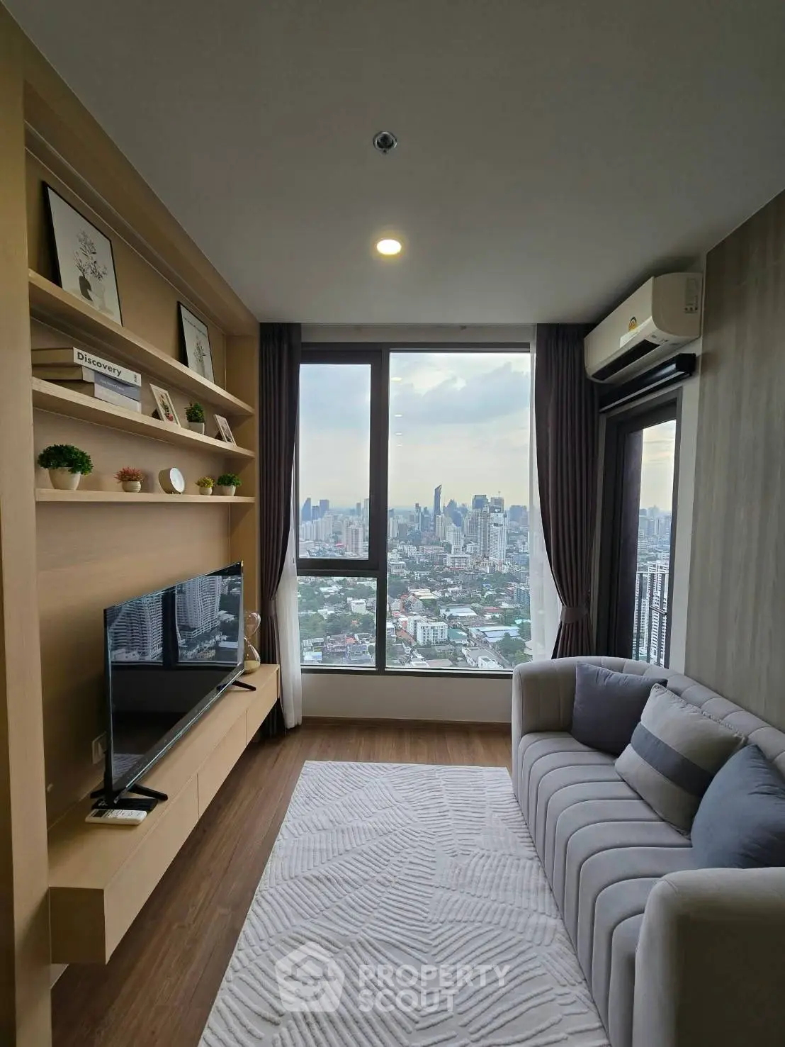 Modern living room with stunning city view, cozy sofa, and stylish decor in high-rise apartment.