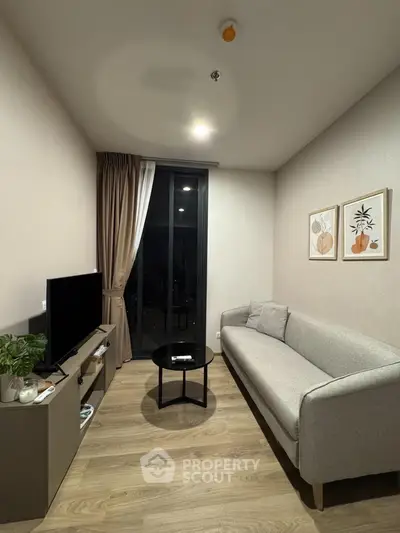 Modern living room with sleek furniture and large window offering natural light.