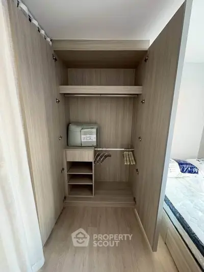 Spacious wooden wardrobe with shelves and hangers in a modern bedroom setting.