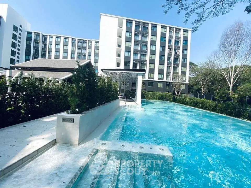 Luxurious apartment complex with stunning outdoor pool and lush greenery.