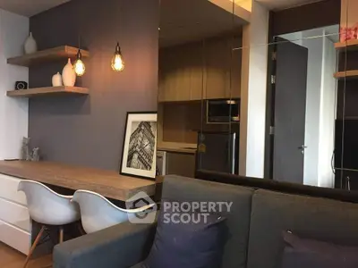 Modern living room with stylish decor and open kitchen layout, featuring elegant lighting and cozy seating.