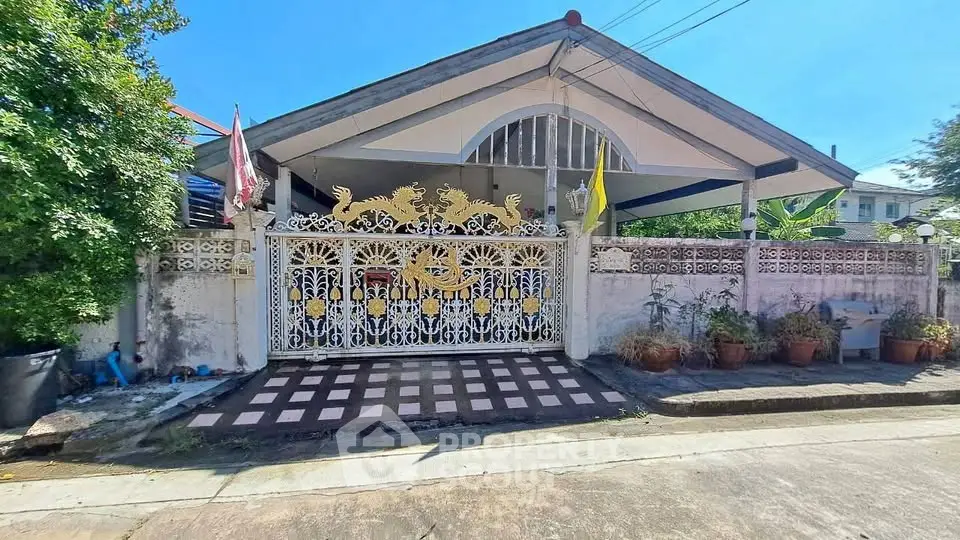 Charming single-story home with decorative gate and lush greenery, perfect for serene living.