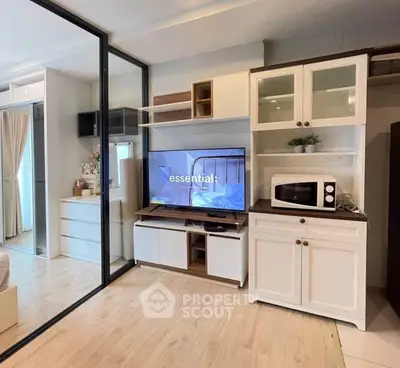Modern living room with stylish cabinetry and built-in TV, featuring a microwave and elegant decor.