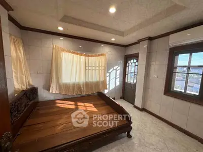 Spacious bedroom with wooden bed and large windows offering natural light.