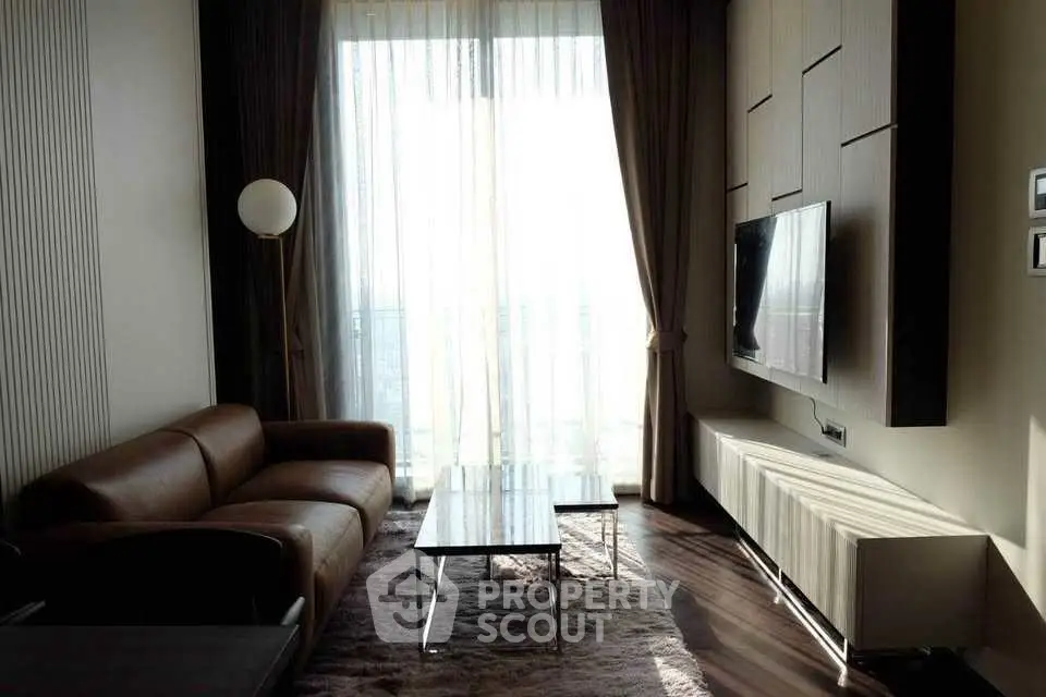 Modern living room with leather sofa, large TV, and floor-to-ceiling windows.