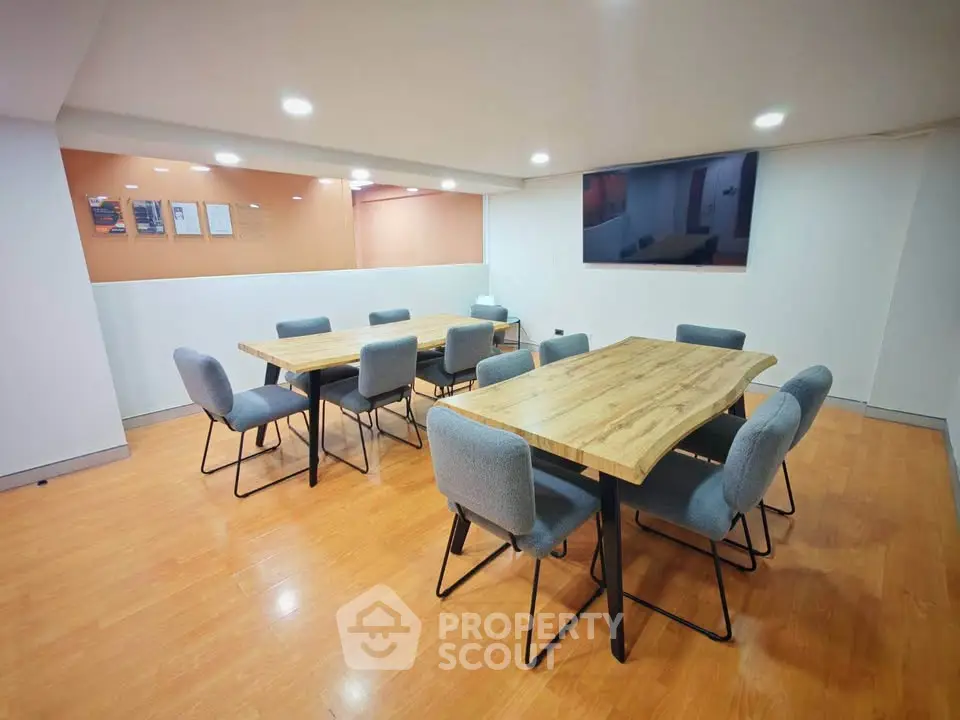 Modern study room with wooden tables and gray chairs, ideal for meetings.