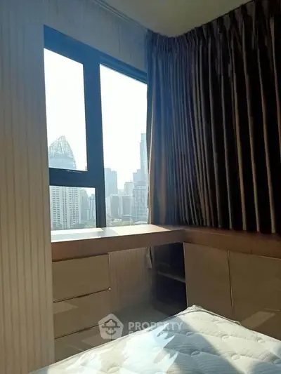 Modern bedroom with city view, featuring large window and stylish curtains, perfect for urban living.