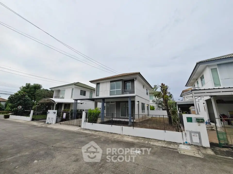 Modern two-story house with spacious driveway and fenced yard in suburban neighborhood.