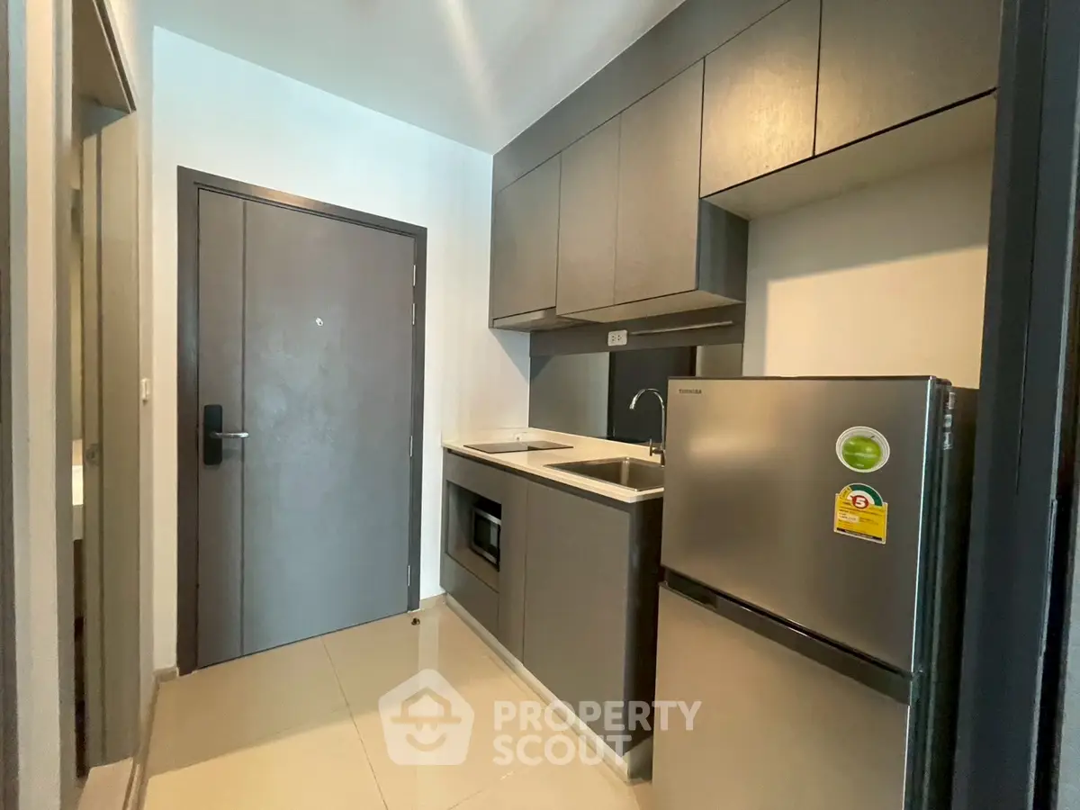 Modern compact kitchen with sleek cabinetry and stainless steel appliances in a stylish apartment.