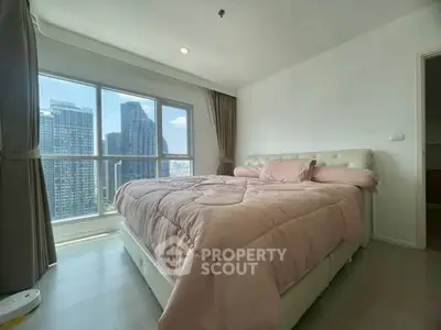 Spacious bedroom with large window offering stunning city view in modern apartment.