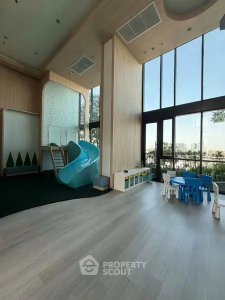 Spacious children's play area with slide and city view in modern building