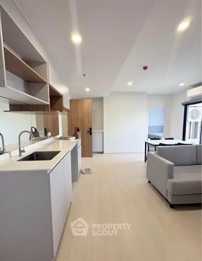 Modern open-layout kitchen and living room with sleek design and ample natural light.