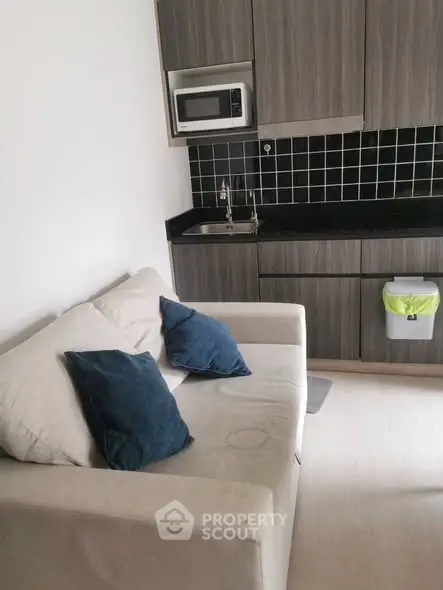 Cozy kitchen with modern cabinetry and compact sofa, perfect for small apartments.