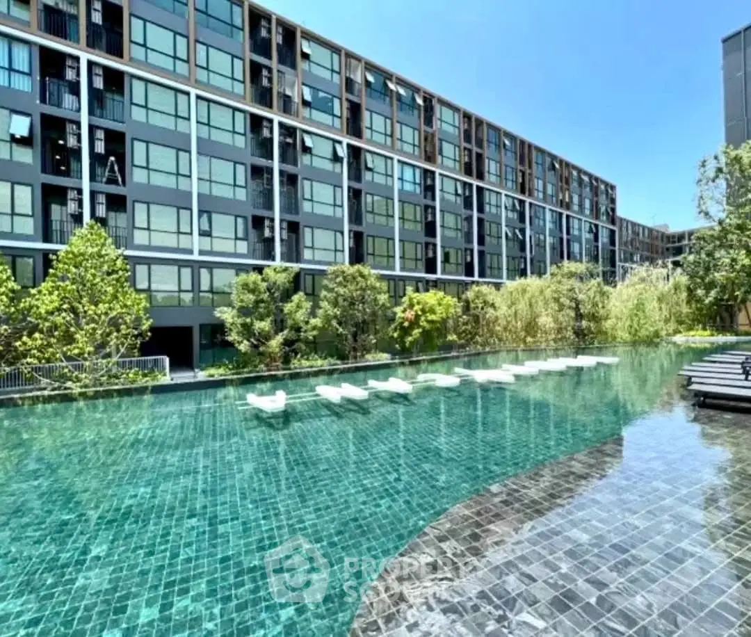 Luxurious modern apartment complex with stunning poolside view and lush greenery.