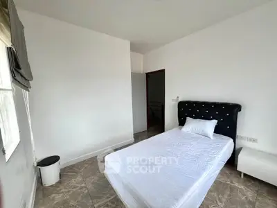 Spacious bedroom with elegant headboard and natural light, perfect for relaxation and comfort.