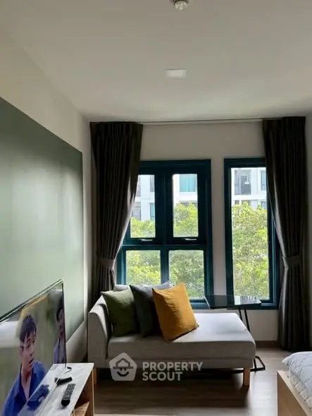 Cozy living room with modern decor and large windows offering a green view.