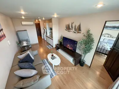 Spacious living room with modern decor and open layout, featuring a cozy sofa and flat-screen TV.