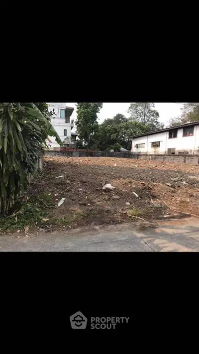 Vacant land plot ideal for development in a residential area with nearby buildings and greenery.