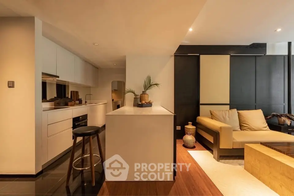 Modern open-layout kitchen and living room with sleek design and warm lighting.