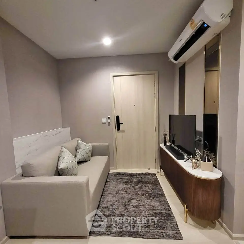 Modern living room with sleek sofa, wall-mounted TV, and air conditioning in a cozy apartment.