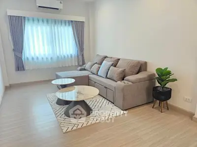Modern living room with stylish sofa and coffee tables, featuring elegant curtains and a cozy atmosphere.
