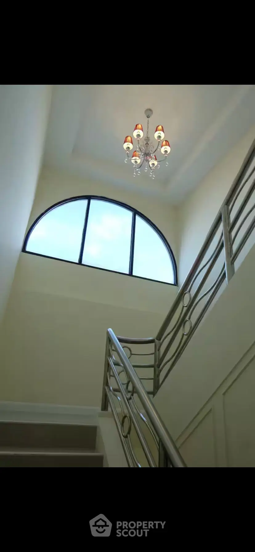 Elegant staircase with modern chandelier and large window in a stylish building