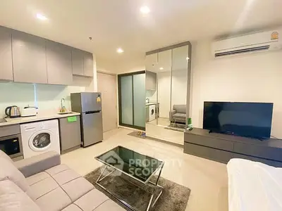 Modern living room with open kitchen, featuring sleek appliances and stylish furniture.