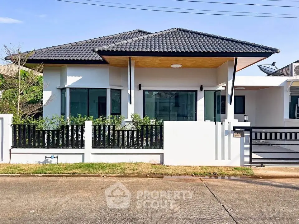 Modern single-story house with sleek design and black roof in a suburban neighborhood.