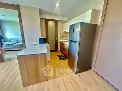 Modern kitchen with sleek appliances and wooden cabinetry in open layout apartment.