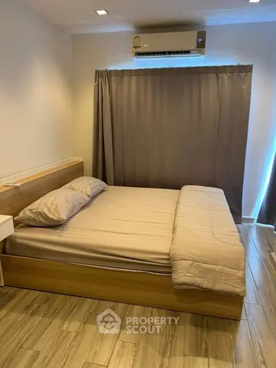 Cozy bedroom with wooden flooring and modern air conditioning unit