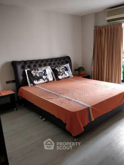 Modern bedroom with stylish bed and natural light, featuring elegant decor and air conditioning.
