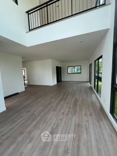 Spacious modern living room with high ceilings and large windows offering natural light.