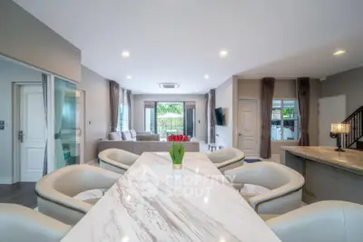 Spacious modern living room with elegant marble dining table and cozy seating area.