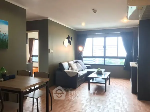 Spacious living room with modern decor and large window offering city view.
