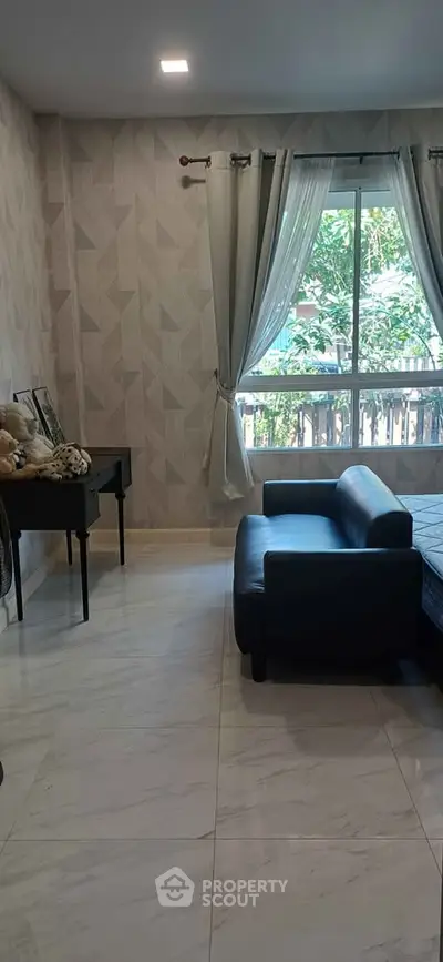 Stylish living room with modern sofa and large window overlooking greenery.