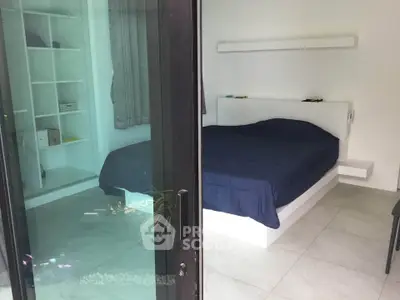 Modern bedroom with sleek design and large glass sliding door for natural light.