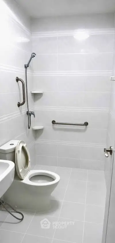 Modern bathroom with white tiles, toilet, and safety handrails, ideal for accessibility.