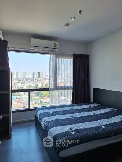 Modern bedroom with city view and large window, featuring stylish decor and ample natural light.