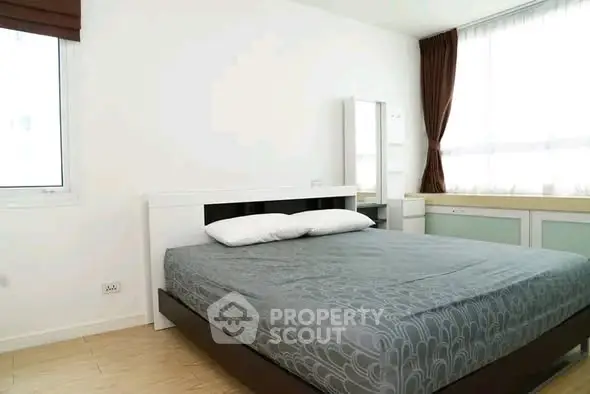 Spacious bedroom with modern decor and large windows for natural light.