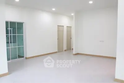 Spacious empty room with modern sliding glass doors and bright lighting, ideal for customization.