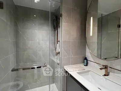 Modern bathroom with sleek design, featuring a glass shower and elegant fixtures.