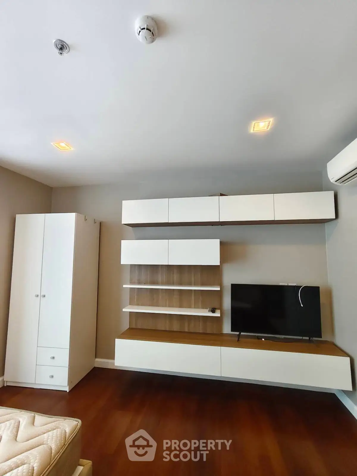 Modern living room with sleek wall-mounted storage and TV unit, featuring hardwood floors and minimalist design.