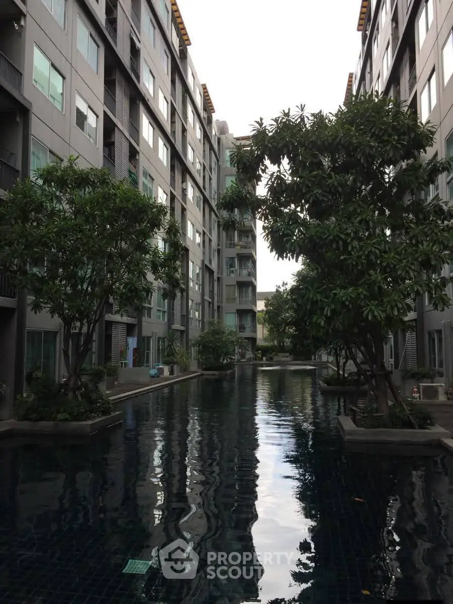 Modern apartment complex with serene pool and lush greenery
