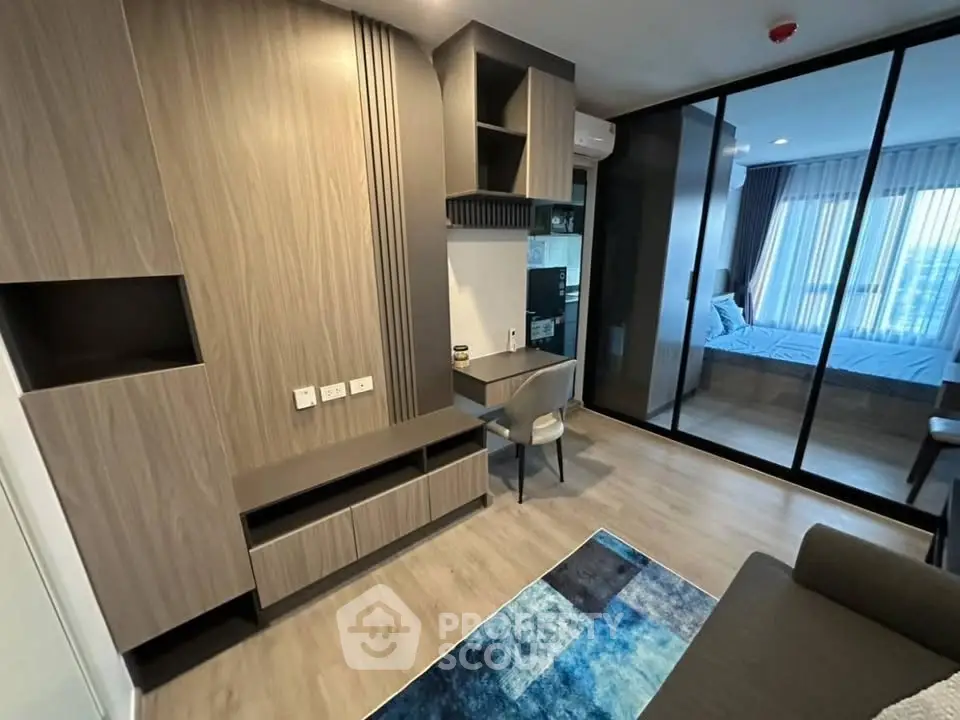 Modern apartment interior with stylish living room and bedroom view, featuring sleek wooden furniture and glass partition.