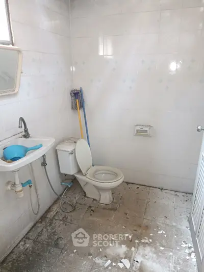 Spacious bathroom with toilet and sink, ideal for renovation opportunities.