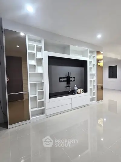 Spacious modern living room with built-in entertainment center and glossy tiled flooring.
