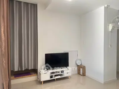 Modern living room with sleek TV setup and elegant curtains in a minimalist design.