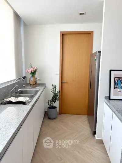 Modern kitchen with sleek countertops and stainless steel fridge in a bright, minimalist design.