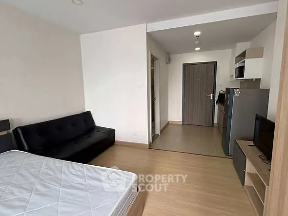 Modern studio apartment with sleek furnishings and open layout, featuring a cozy living area and compact kitchen.